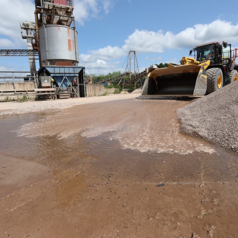 Wassernachfüllen im Werk Radlader lässt Wasser in ein flaches Laichgewässer mit Kaulquappen